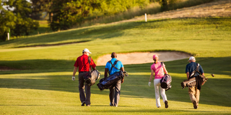 Image of four people walking along a golf course